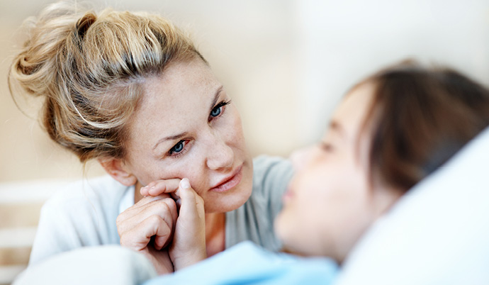 mom looking at daughter in hospital bed